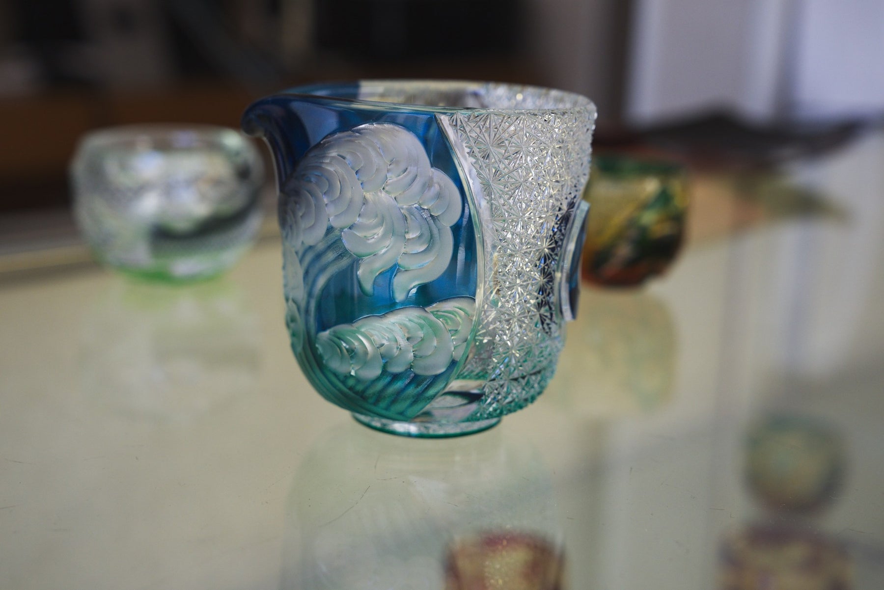 Blue glass cup with a carved wave and cloud relief, Haku Glass showroom