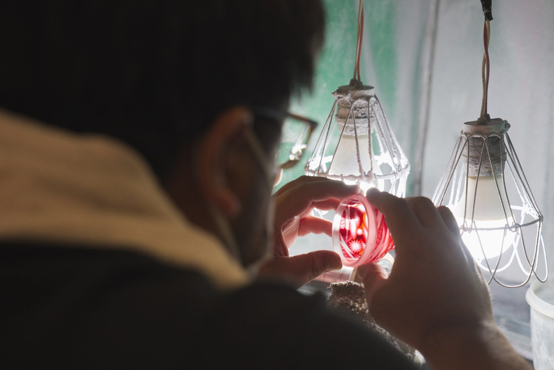 Hands holding a glass piece to the light, colour fading into clear, bokashi gradient